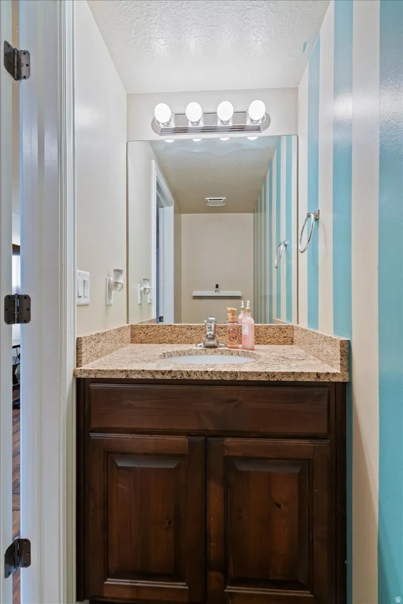 1/2 Bathroom with vanity and a textured ceiling