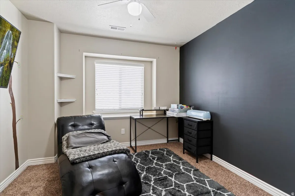 Carpeted office with ceiling fan and a textured ceiling
