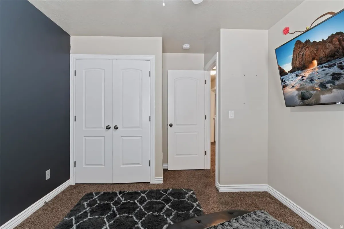 Bedroom with dark carpet, a closet, and ceiling fan
