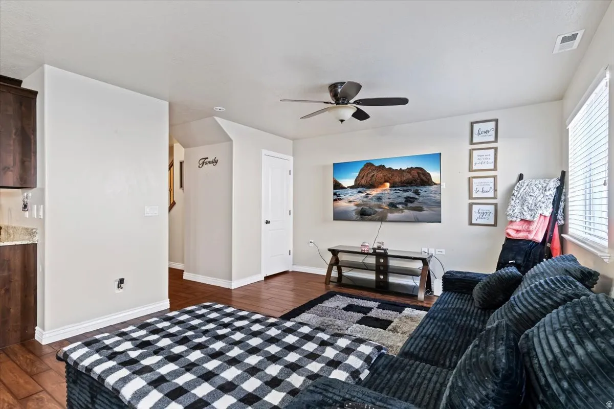 Living area with dark wood-type flooring and a ceiling fan
