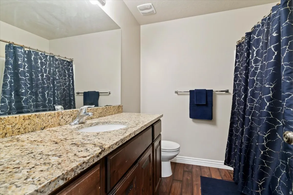 Full bathroom with a shower with shower curtain, vanity, and dark wood-style flooring