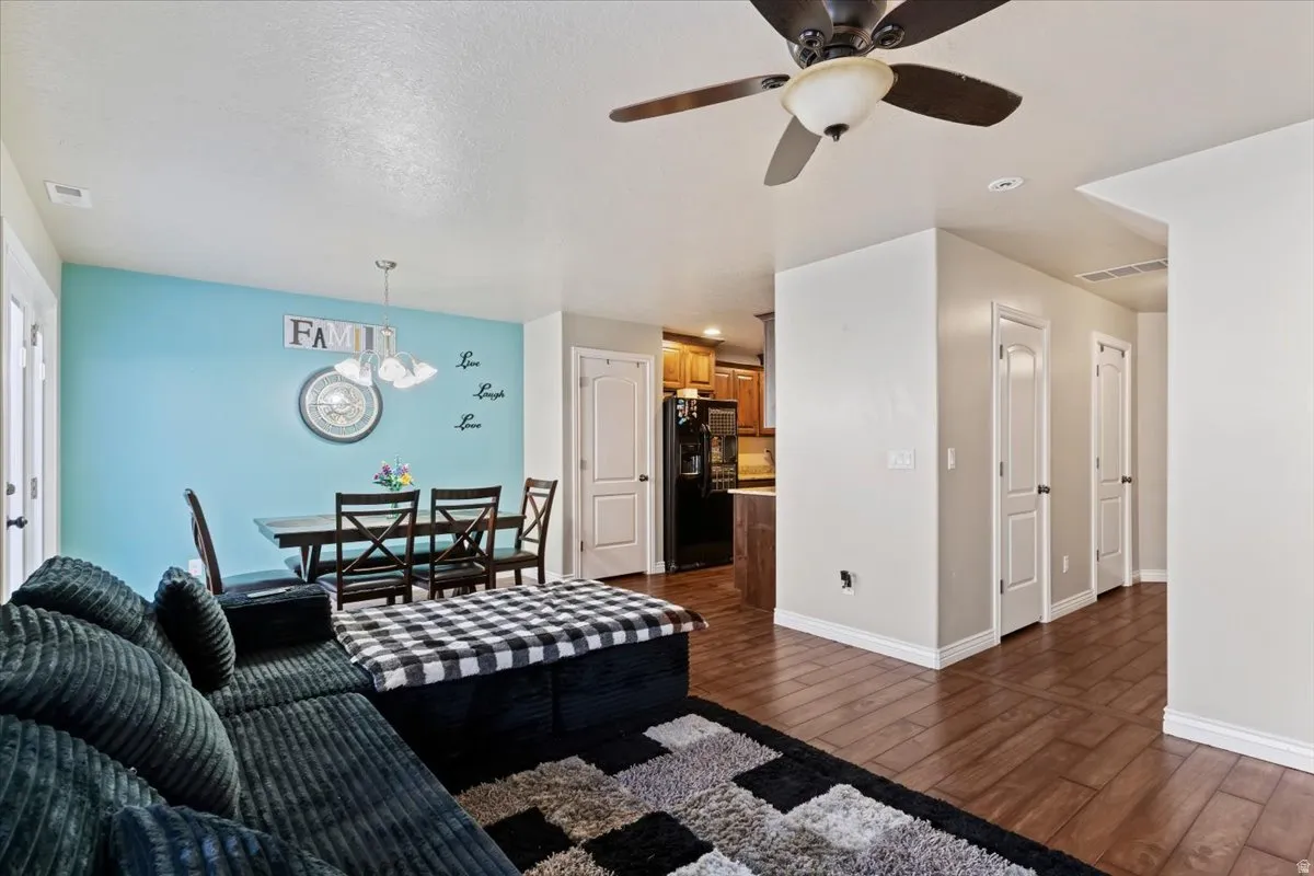 Living area with dark wood-style flooring, suspended lighting, and a ceiling fan