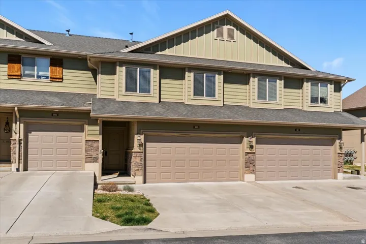 View of front of home with board and batten siding, roof with shingles, an attached garage, and concrete driveway
