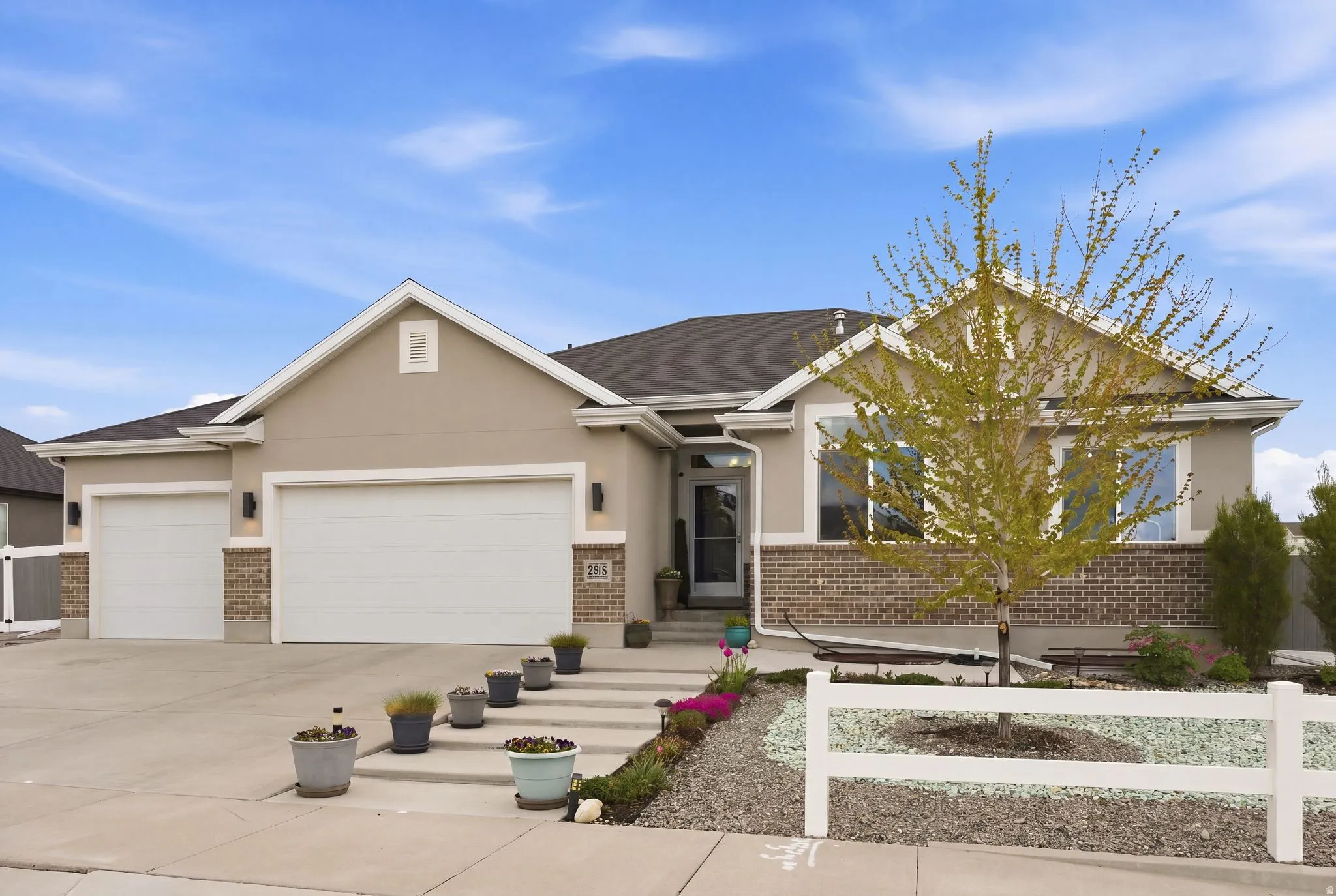 View of front of property with brick siding, an attached garage, driveway, and stucco siding