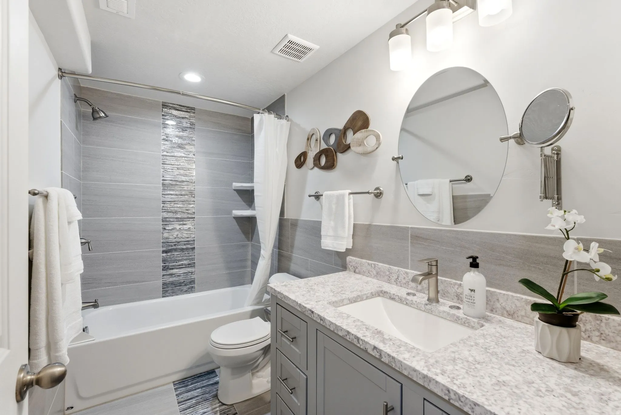 Bathroom with vanity, tile walls, shower / tub combo with curtain, and wainscoting