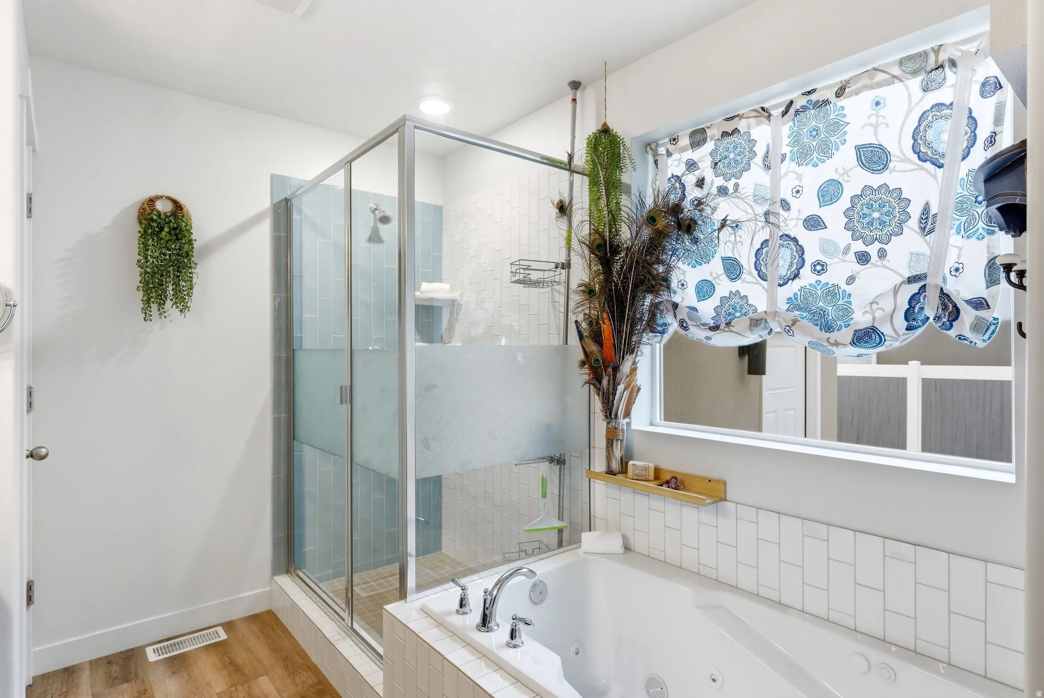 Bathroom featuring a jetted tub, a stall shower, and light wood finished floors