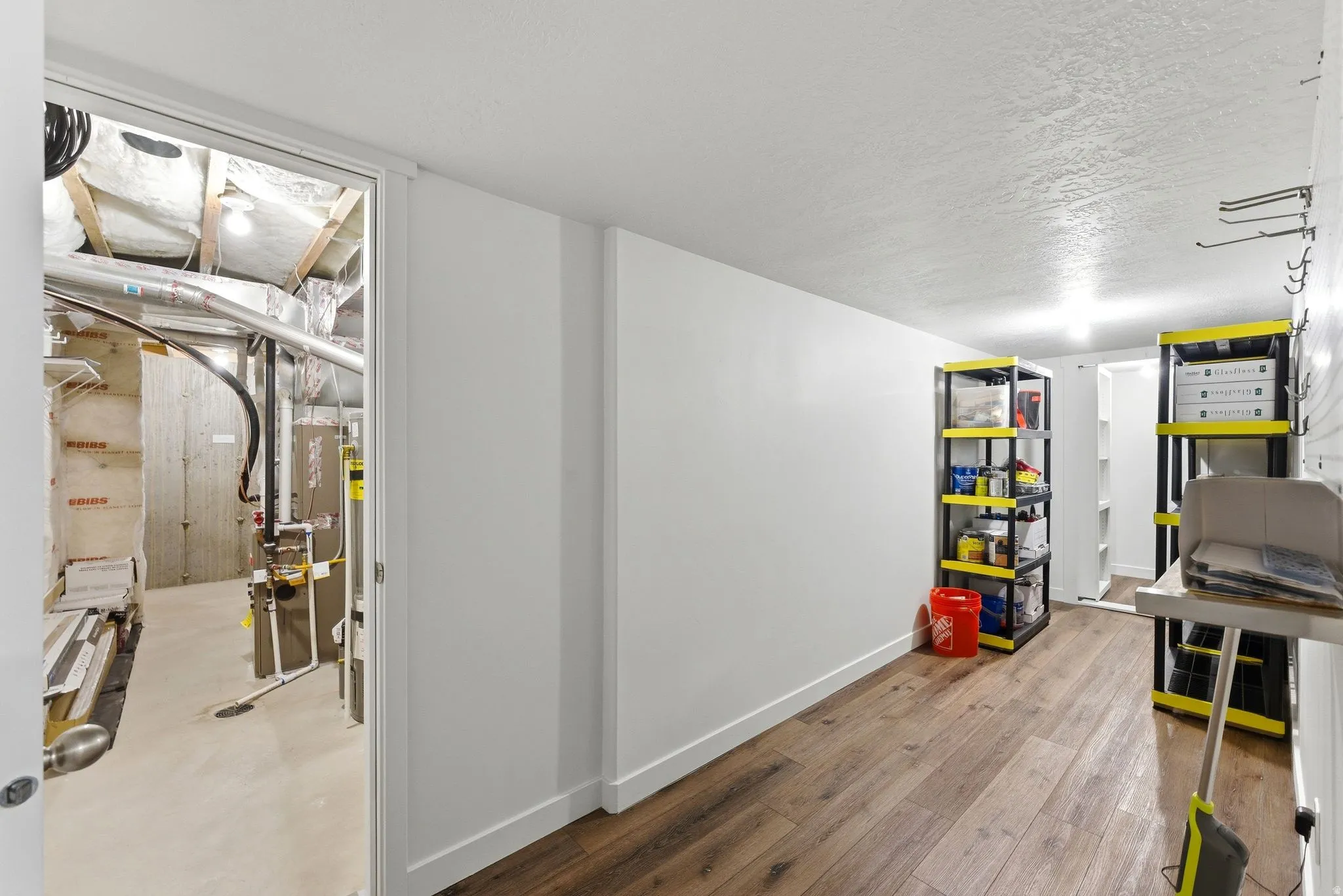 Finished below grade area with a textured ceiling and light wood-type flooring