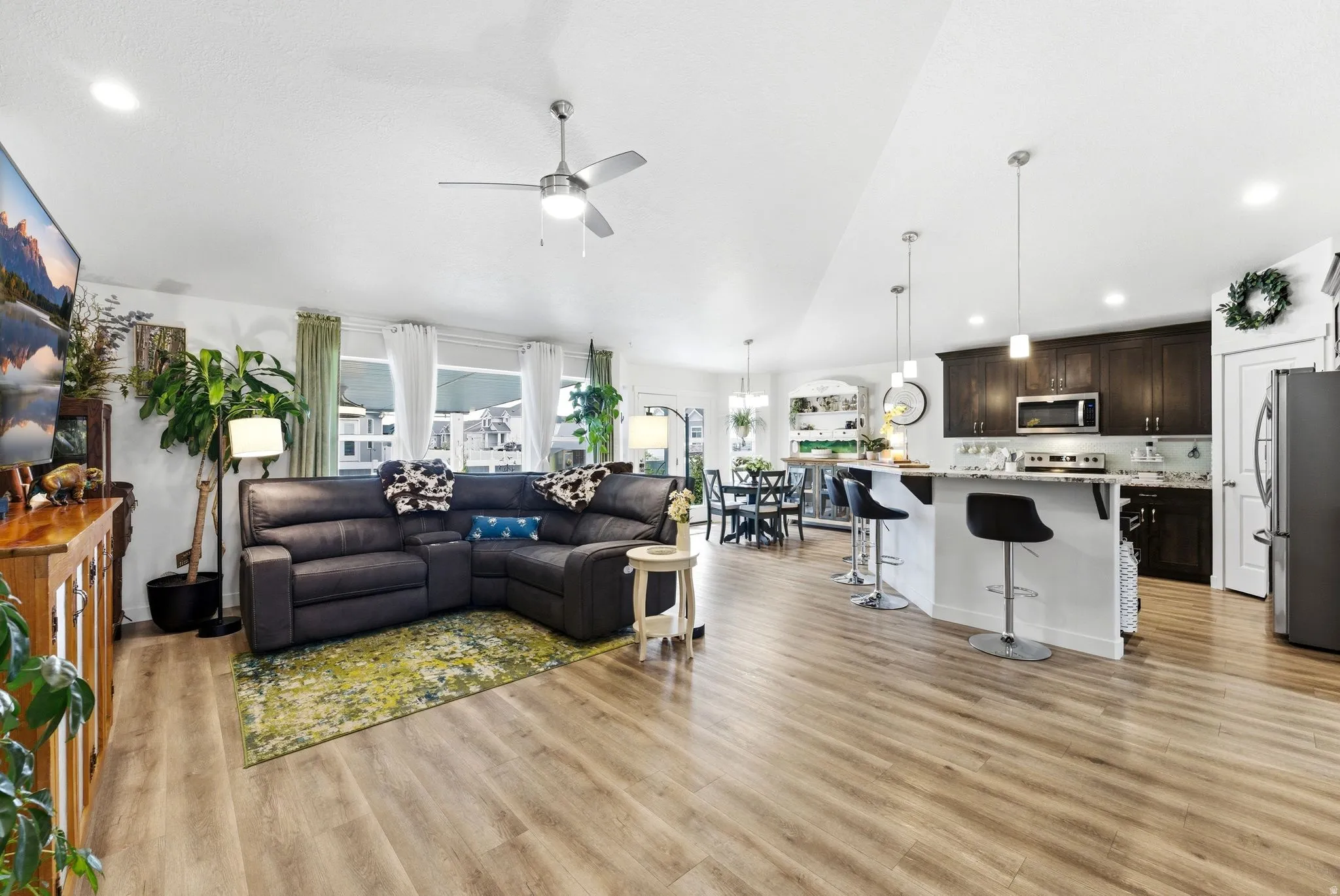 Living room featuring vaulted ceiling, a ceiling fan, light wood-style floors, and recessed lighting