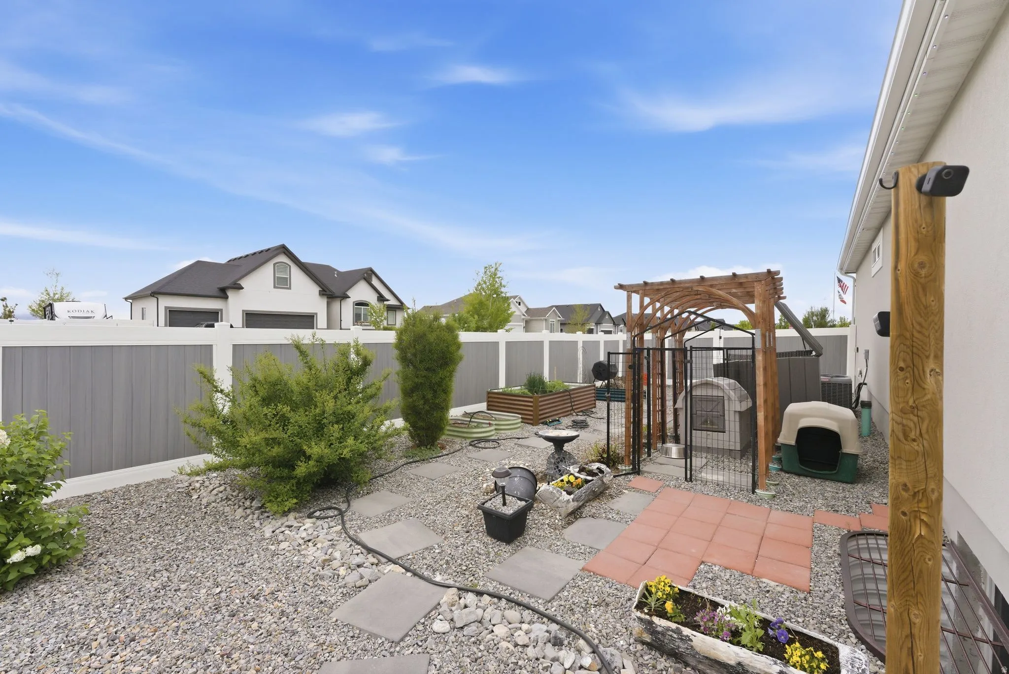 Fenced backyard featuring a patio area, a residential view, and a vegetable garden