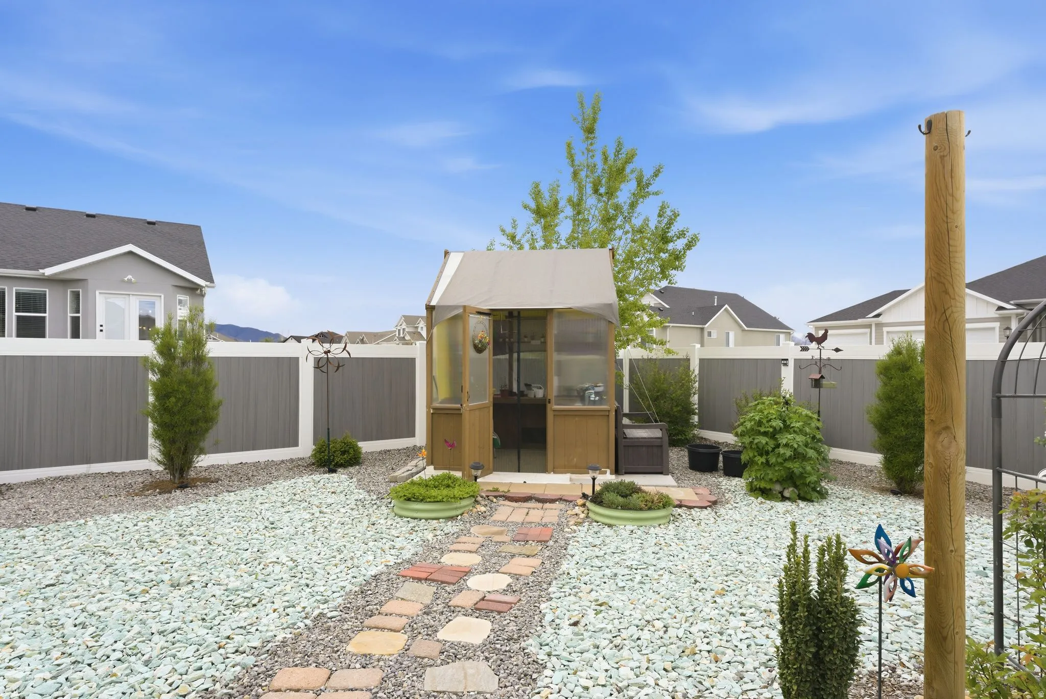 Fenced backyard with a sunroom, an outdoor structure, and a greenhouse