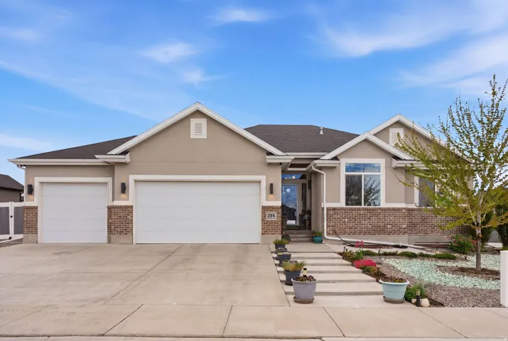View of front of house with brick siding, a garage, stucco siding, driveway, and roof with shingles
