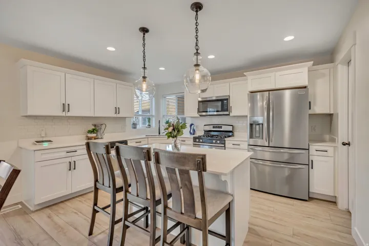 Kitchen with stainless steel appliances, white cabinetry, a kitchen bar, and light wood-type flooring