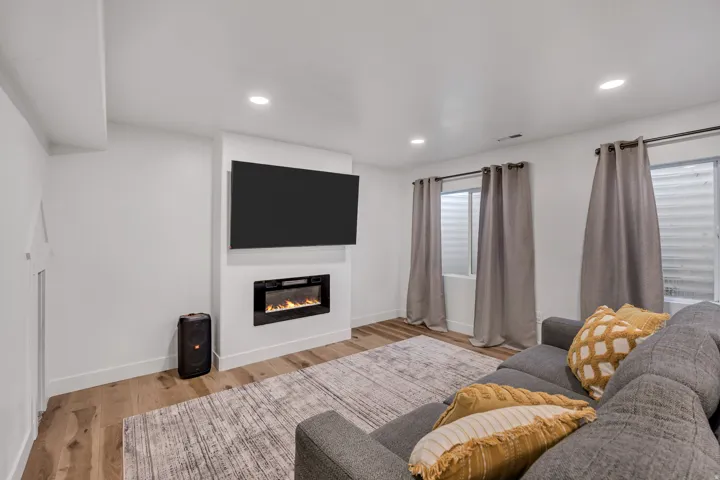 Living room featuring light wood-type flooring, a glass covered fireplace, and recessed lighting