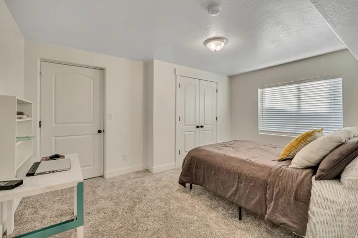 Bedroom featuring light carpet, a textured ceiling, and a closet