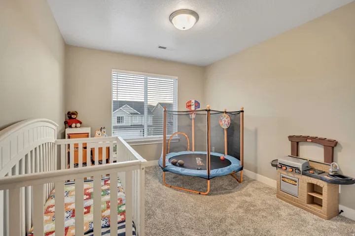 Bedroom featuring carpet, a textured ceiling, and a crib