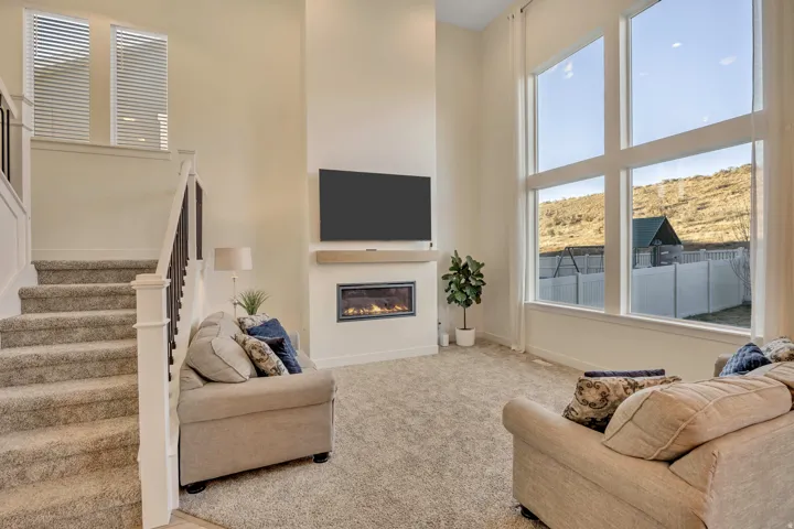 Carpeted living area featuring a high ceiling and a glass covered fireplace