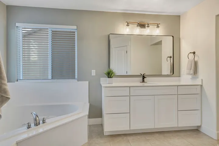 Full bath with vanity, a bath, and light tile patterned floors