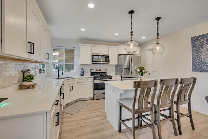 Kitchen with stainless steel appliances, light wood finished floors, white cabinetry, a kitchen breakfast bar, and a kitchen island