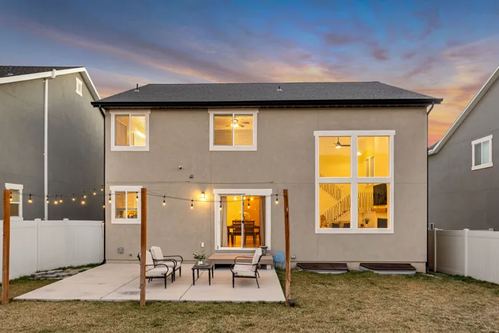 Back of house at dusk with a fenced backyard, a patio area, stucco siding, and roof with shingles
