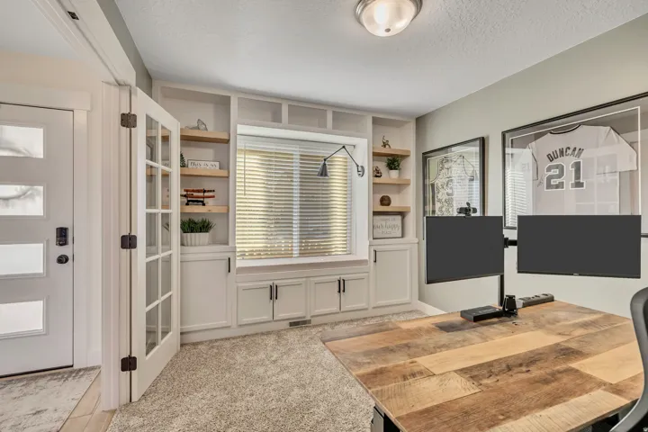 Office space featuring light colored carpet, a textured ceiling, and built in features