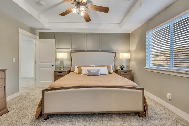 Bedroom featuring a tray ceiling, a ceiling fan, and light carpet