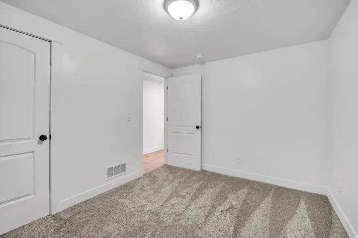 Unfurnished bedroom featuring light colored carpet, a closet, and a textured ceiling
