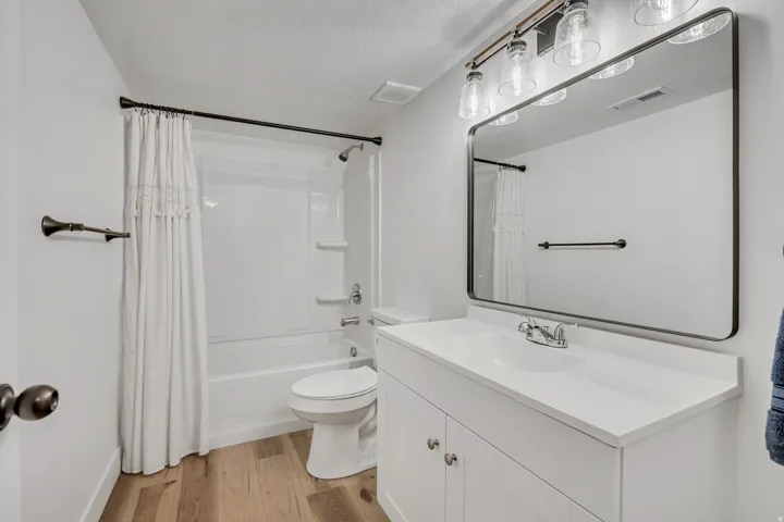 Full bathroom featuring vanity, light wood-style floors, shower / bath combo with shower curtain, and a textured ceiling
