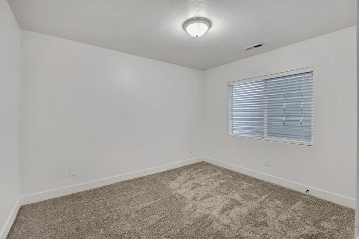 Carpeted spare room featuring baseboards and a textured ceiling