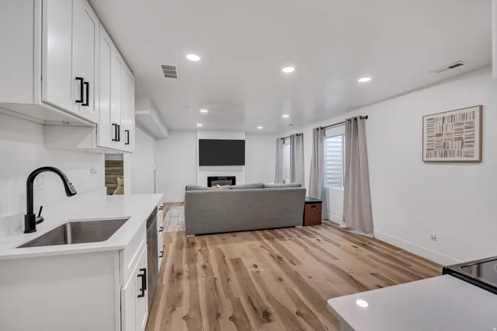 Kitchen with open floor plan, white cabinets, a glass covered fireplace, recessed lighting, and light wood-type flooring