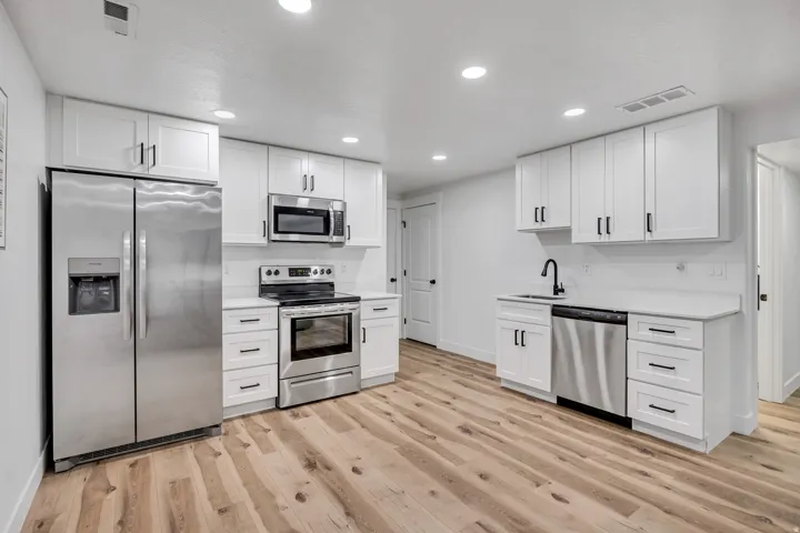 Kitchen featuring stainless steel appliances, white cabinets, light wood-type flooring, and recessed lighting