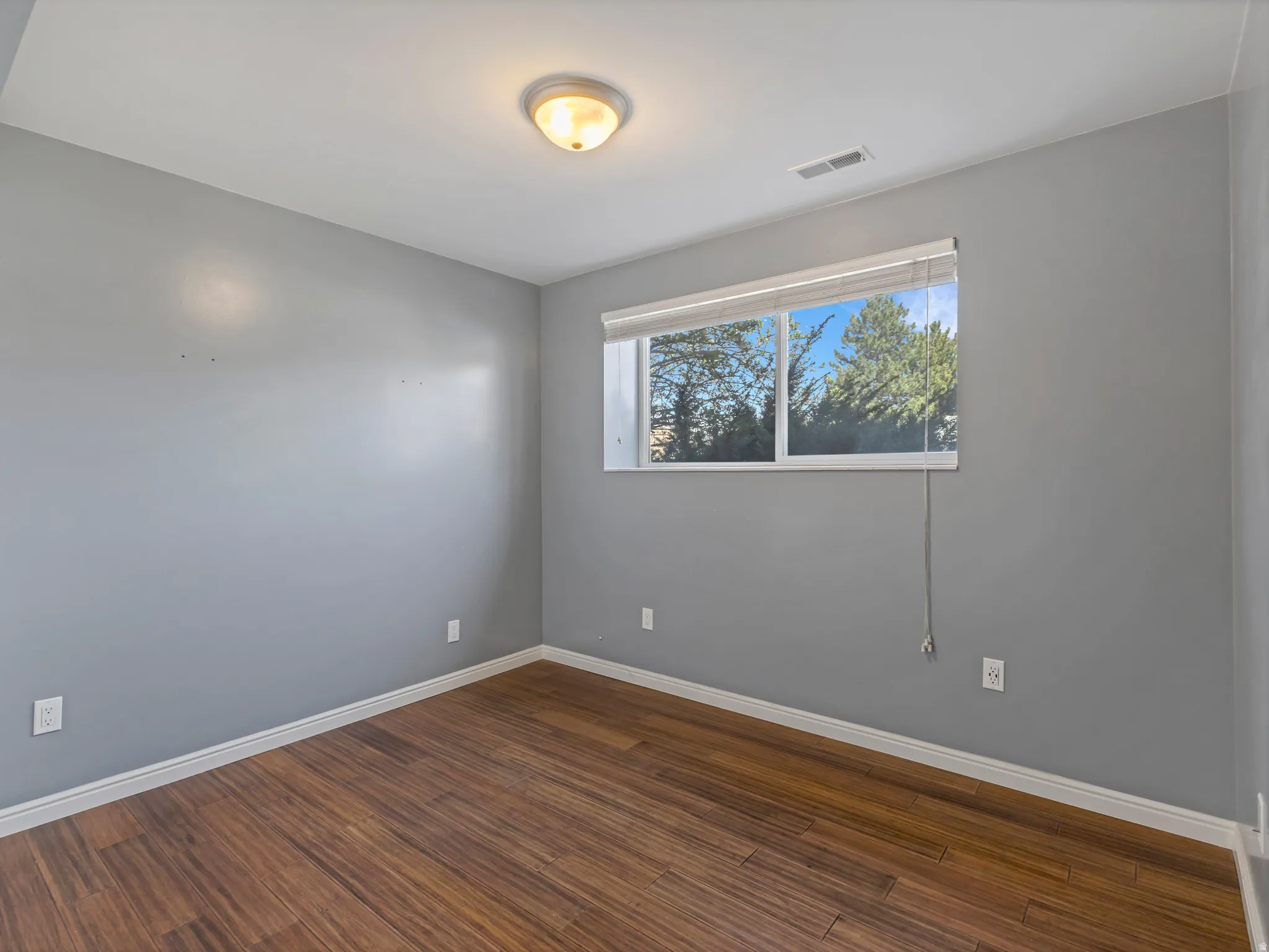 Spare room with dark wood-type flooring and baseboards