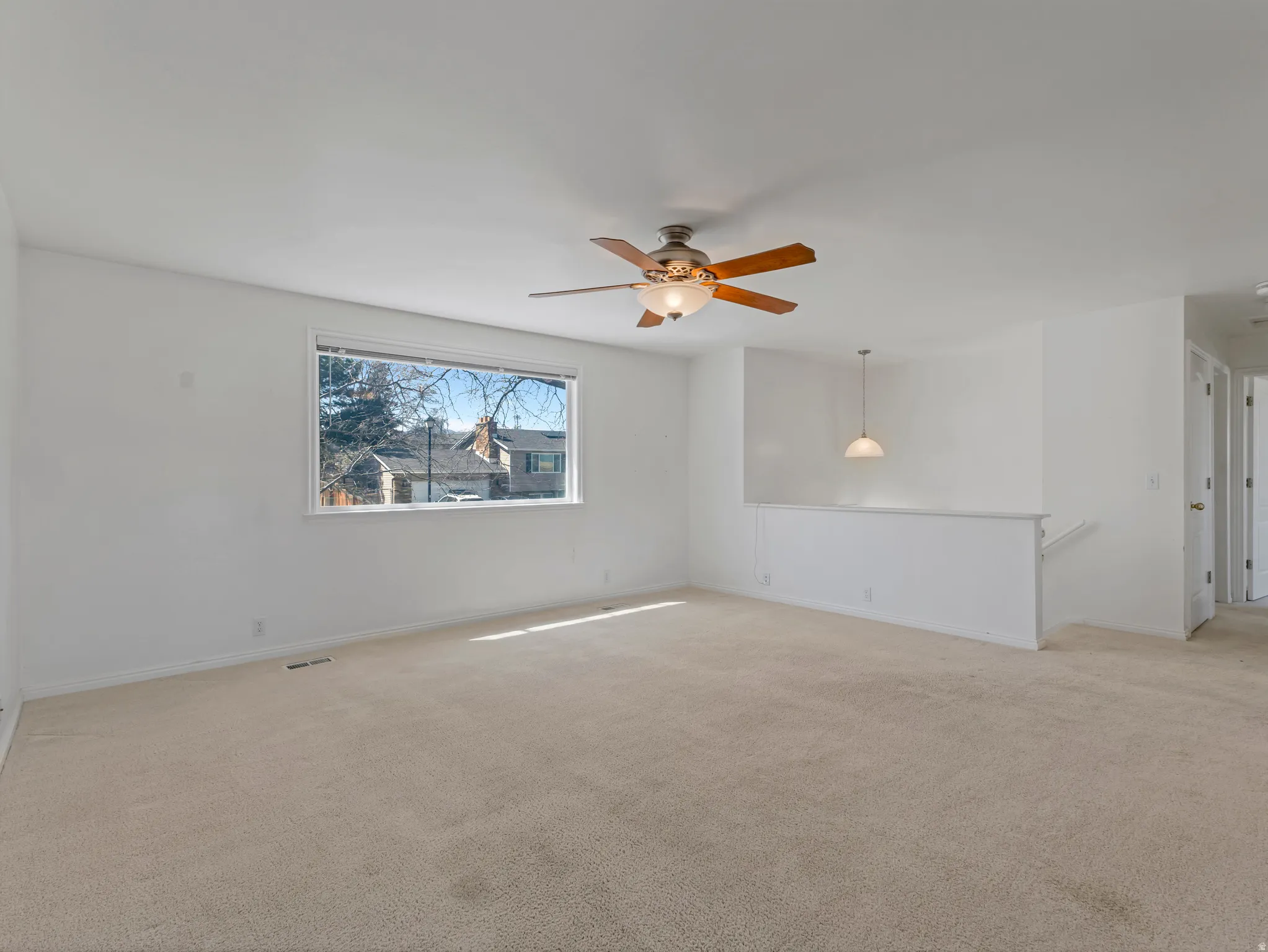 Empty room with ceiling fan and light colored carpet