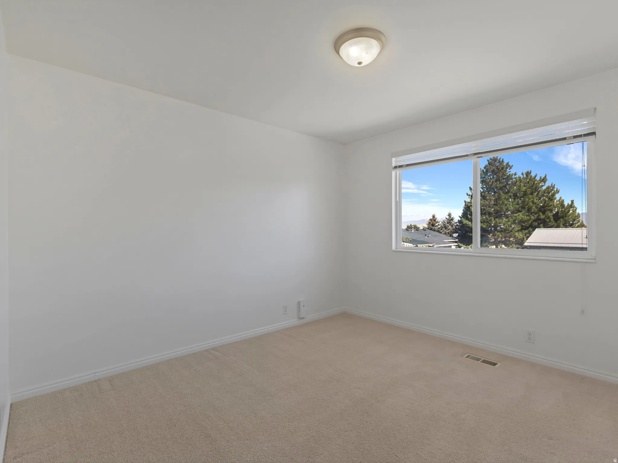 Spare room featuring light colored carpet and baseboards