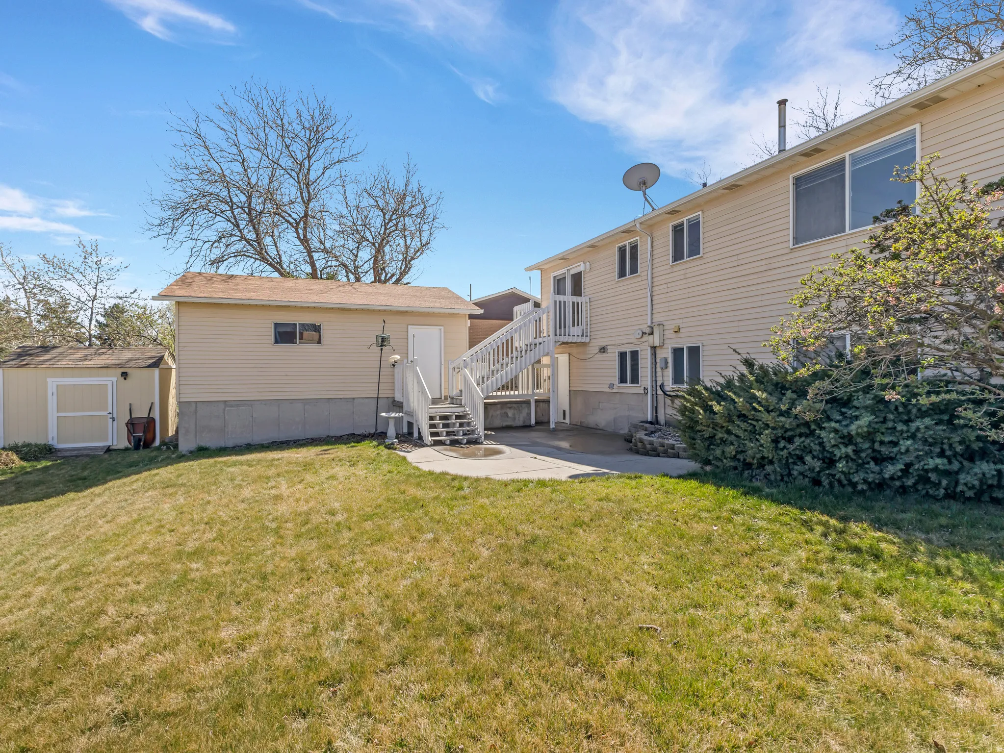 Back of house with a storage unit, a lawn, and a patio area