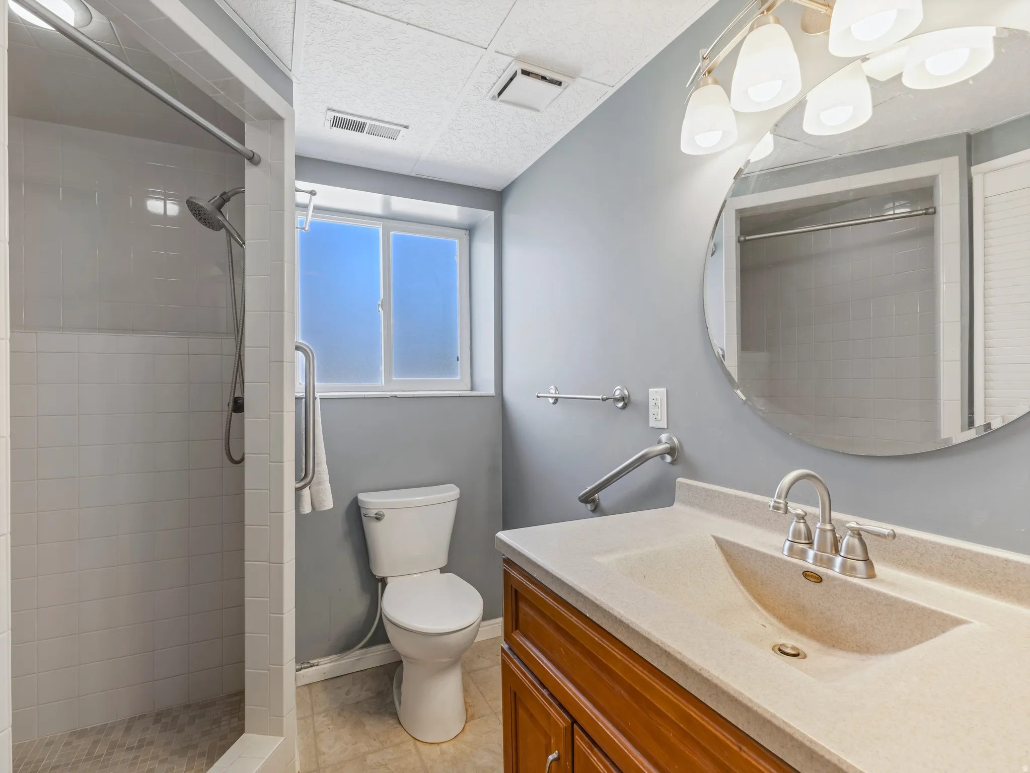 Bathroom featuring vanity, light tile patterned flooring, and a stall shower