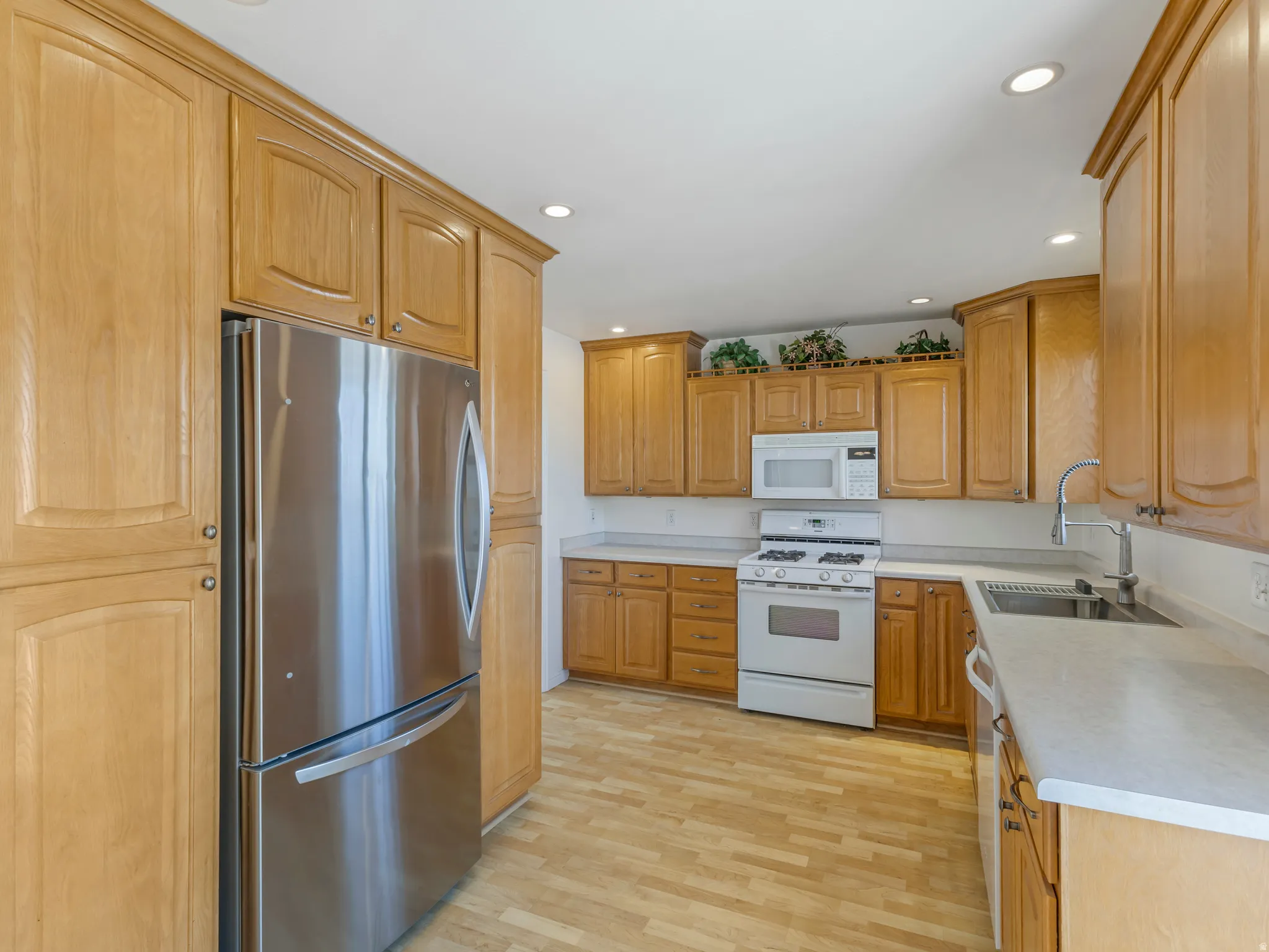 Kitchen with white appliances, recessed lighting, light wood finished floors, and light countertops