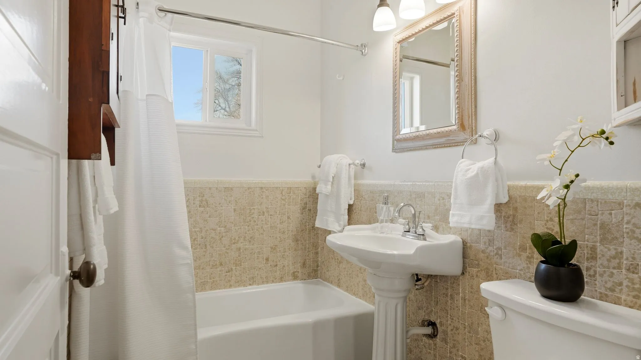 Bathroom with tile walls and shower / bath combination with curtain