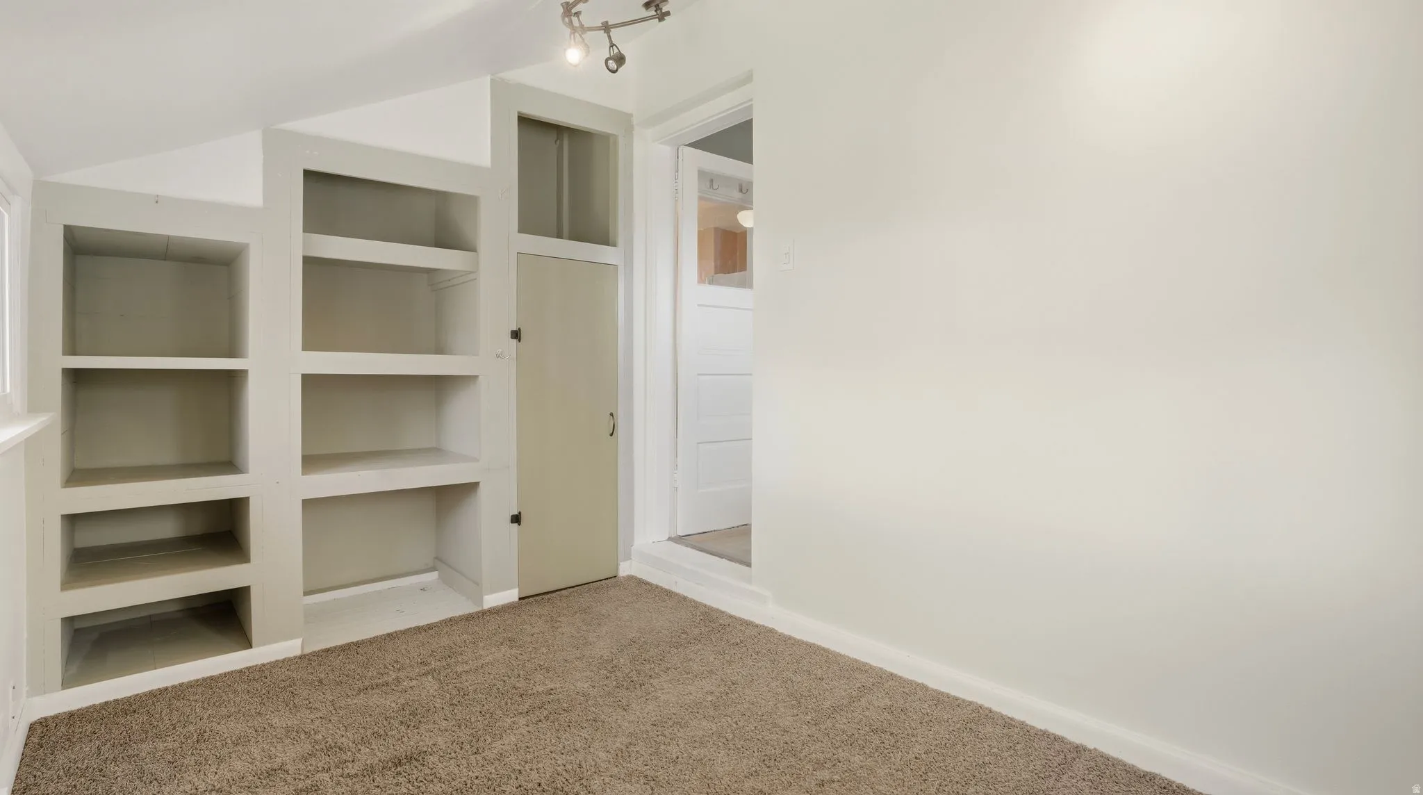 Walk in closet with light colored carpet and vaulted ceiling