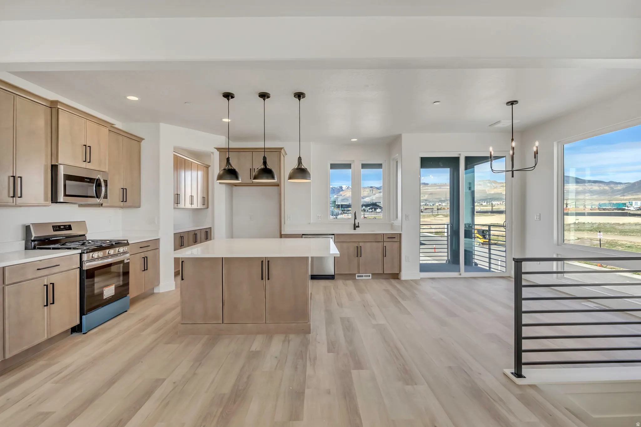 Kitchen with light wood finish cabinets, stainless steel appliances, a kitchen island, and light wood finished floors