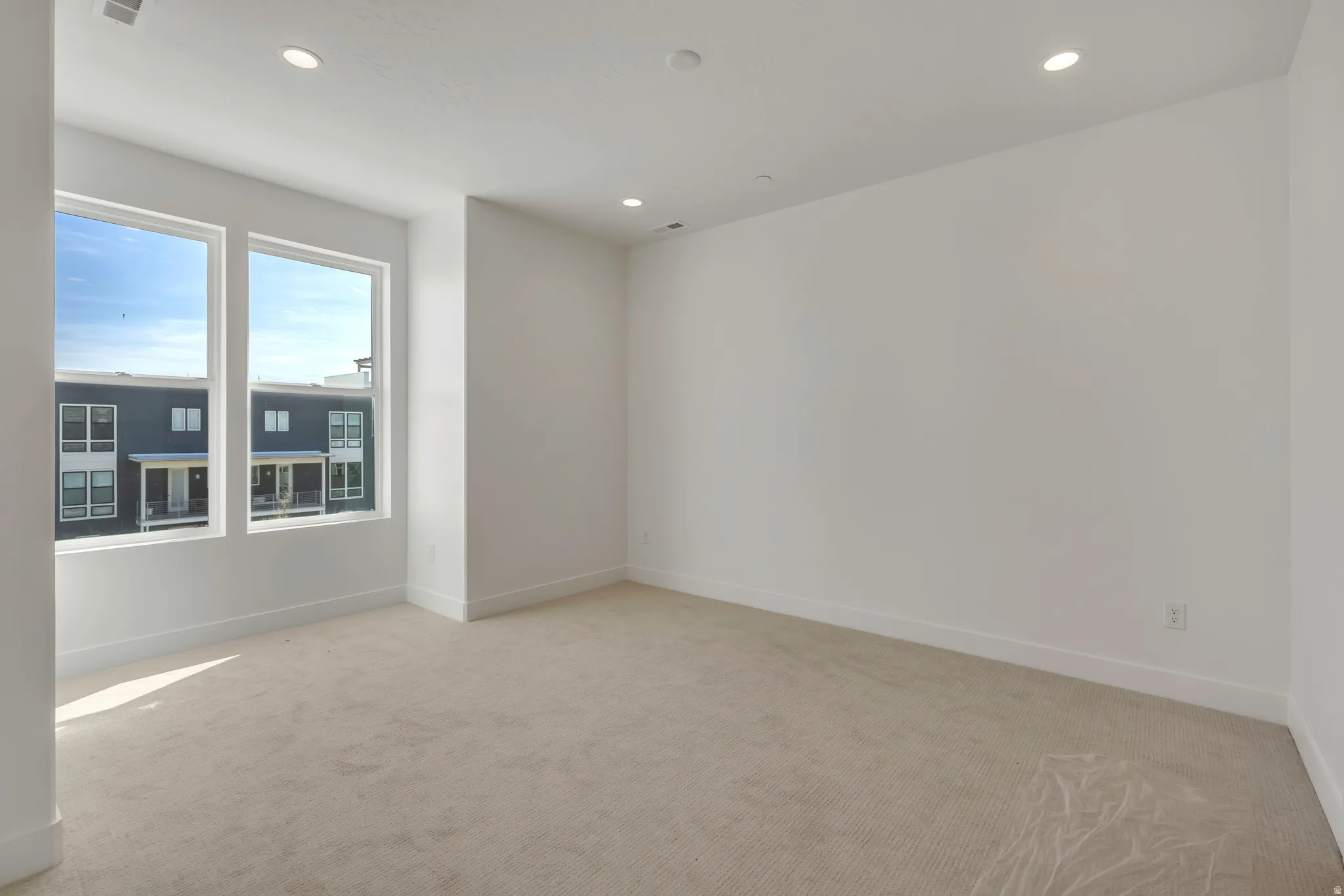 Unfurnished room with light colored carpet and recessed lighting
