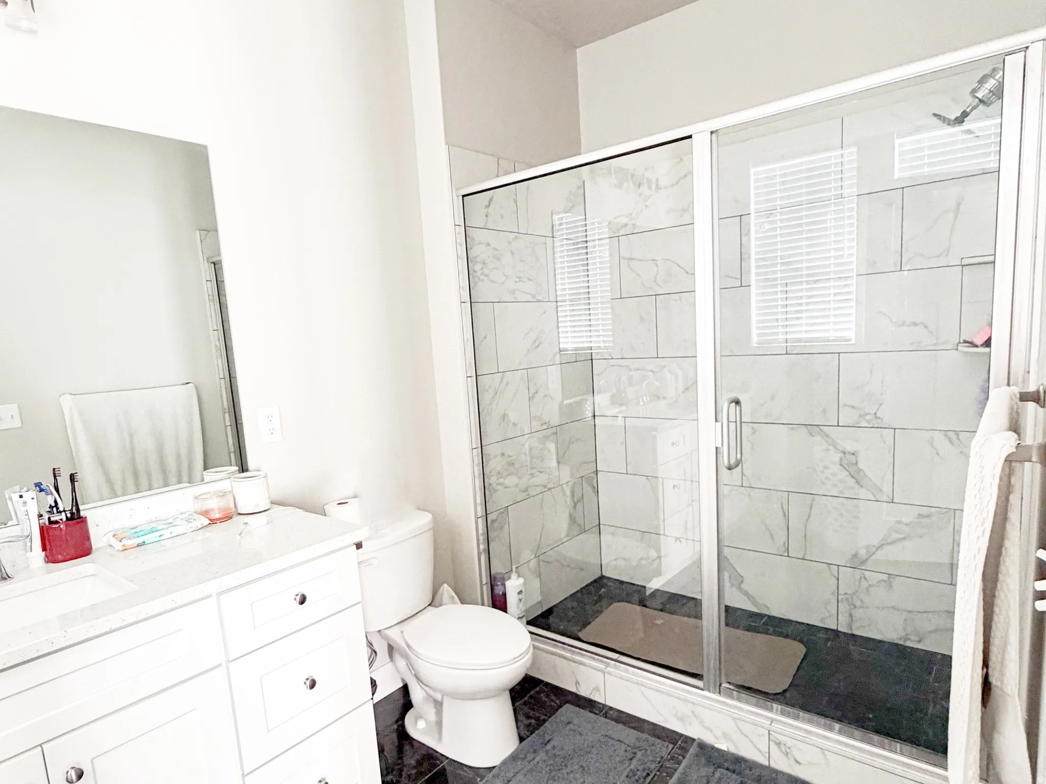 Master Bathroom featuring vanity, a shower stall, and dark marble look finish flooring