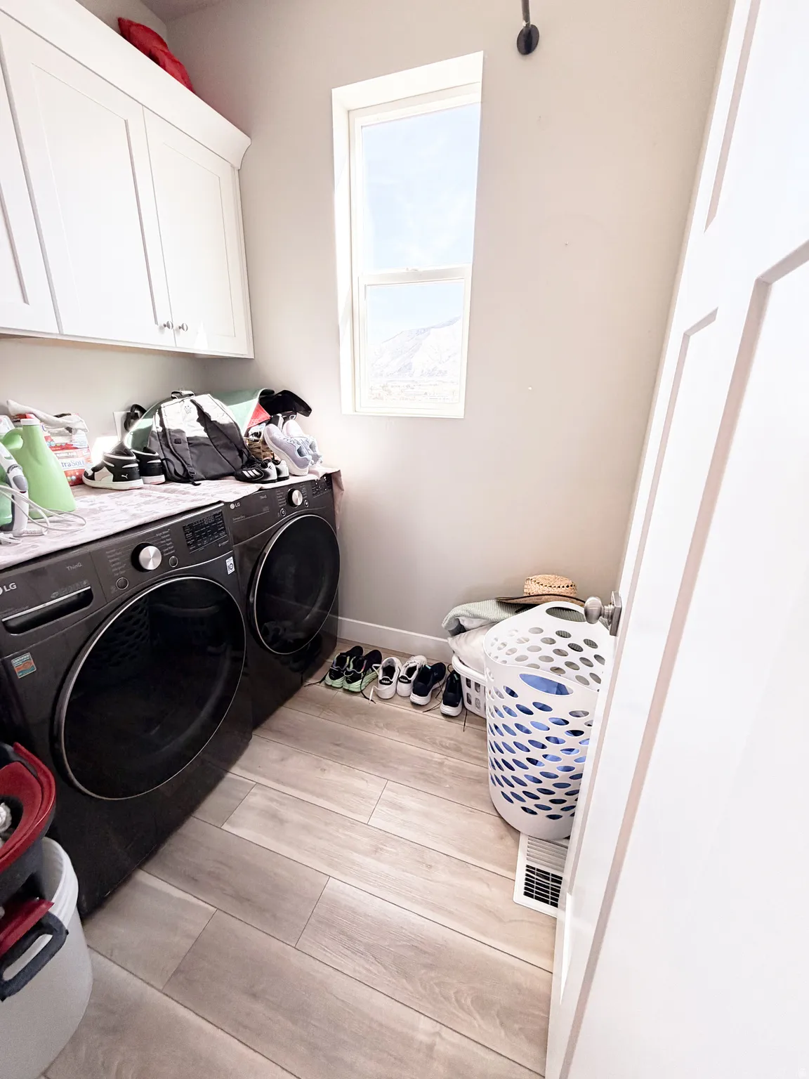 Laundry room featuring cabinet space, light wood-style flooring, and separate washer and dryer