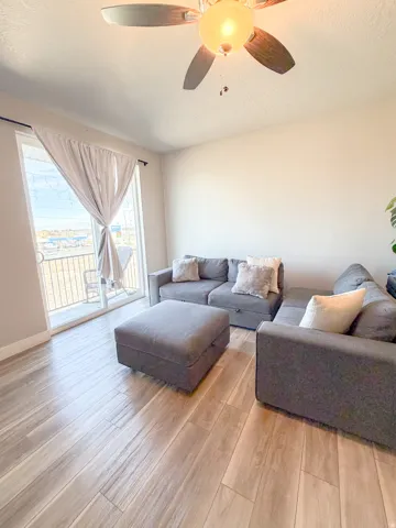 Living area with ceiling fan, light wood-type flooring, and a textured ceiling