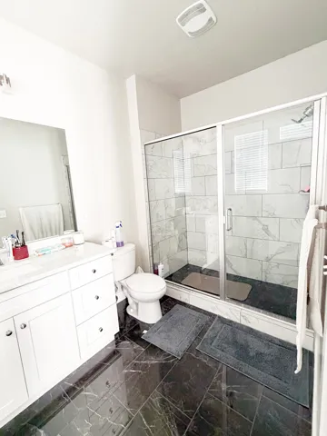 Full bath with vanity, a shower stall, and dark marble finish flooring