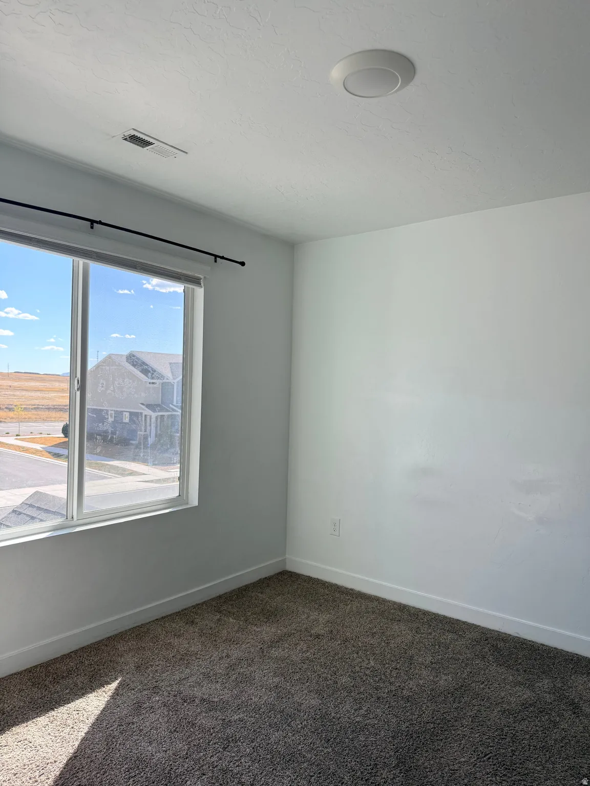 Spare room featuring baseboards and dark carpet