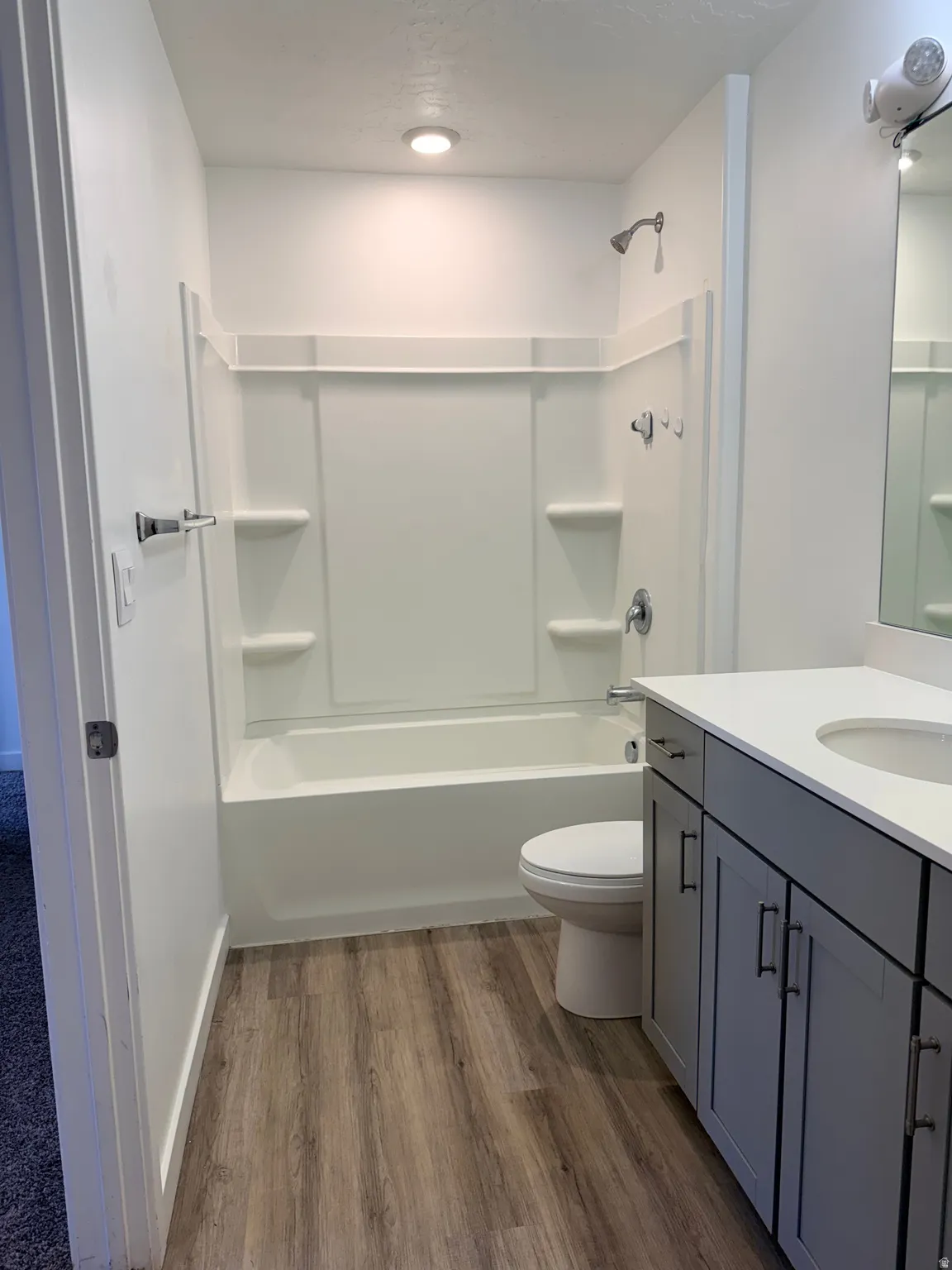 Bathroom with vanity, dark wood-type flooring, and bathtub / shower combination