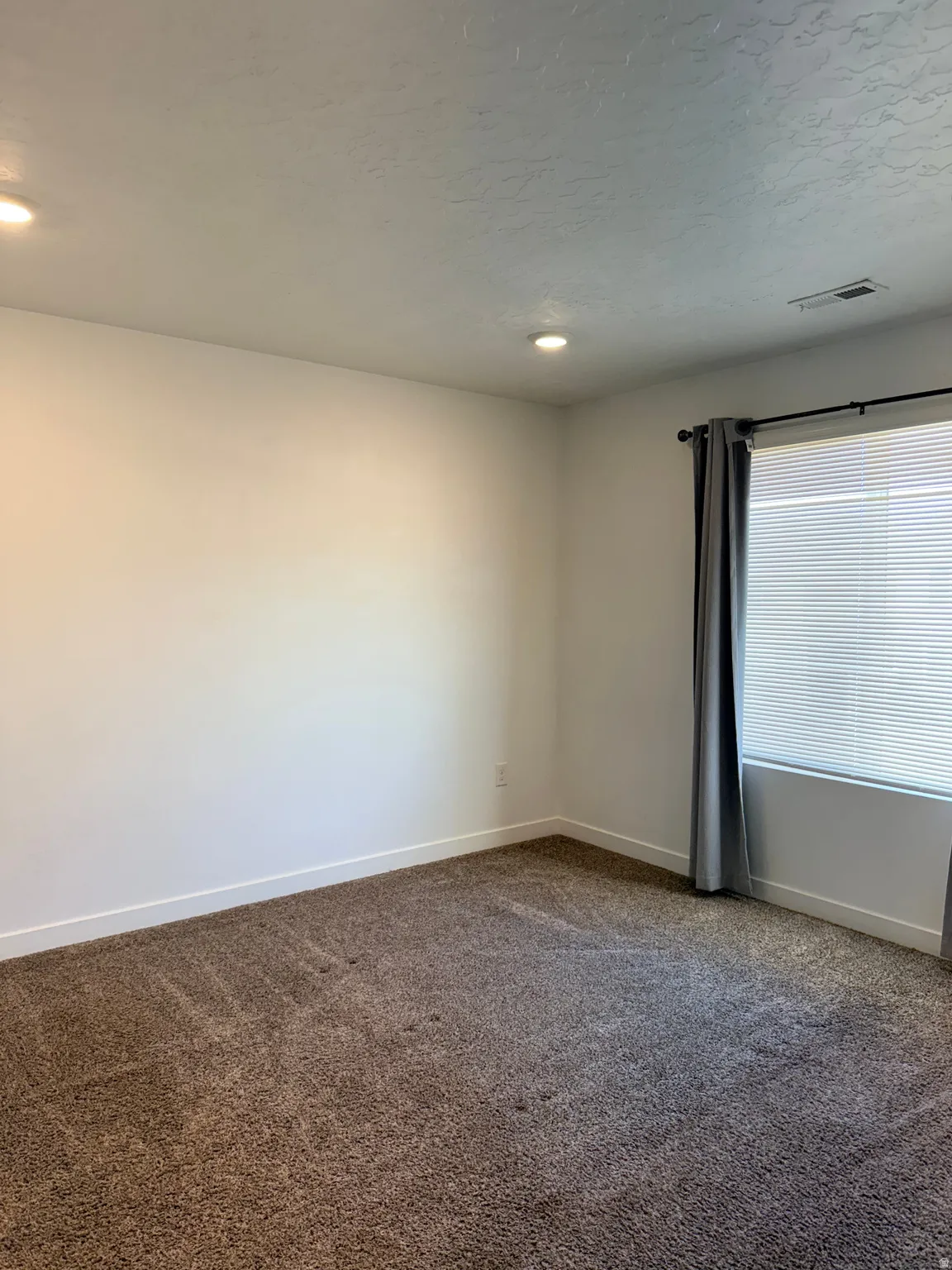 Spare room featuring baseboards and dark colored carpet