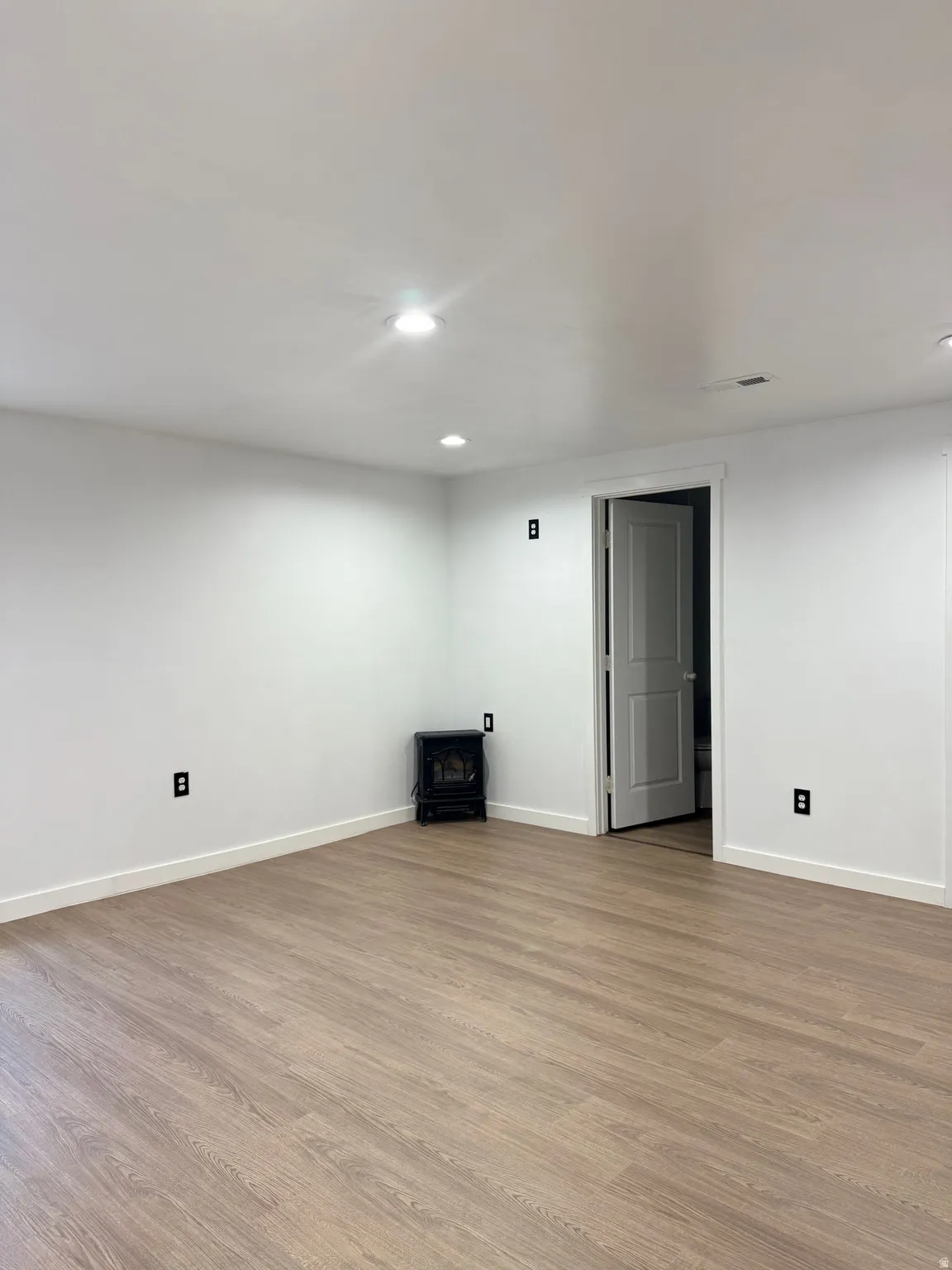 Finished below grade area featuring wood finished floors, recessed lighting, and a wood stove