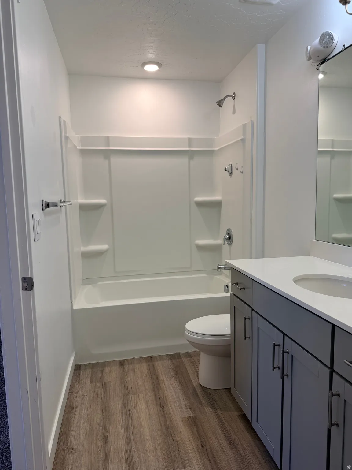 Full bath featuring dark wood-style flooring, vanity, a textured ceiling, and washtub / shower combination