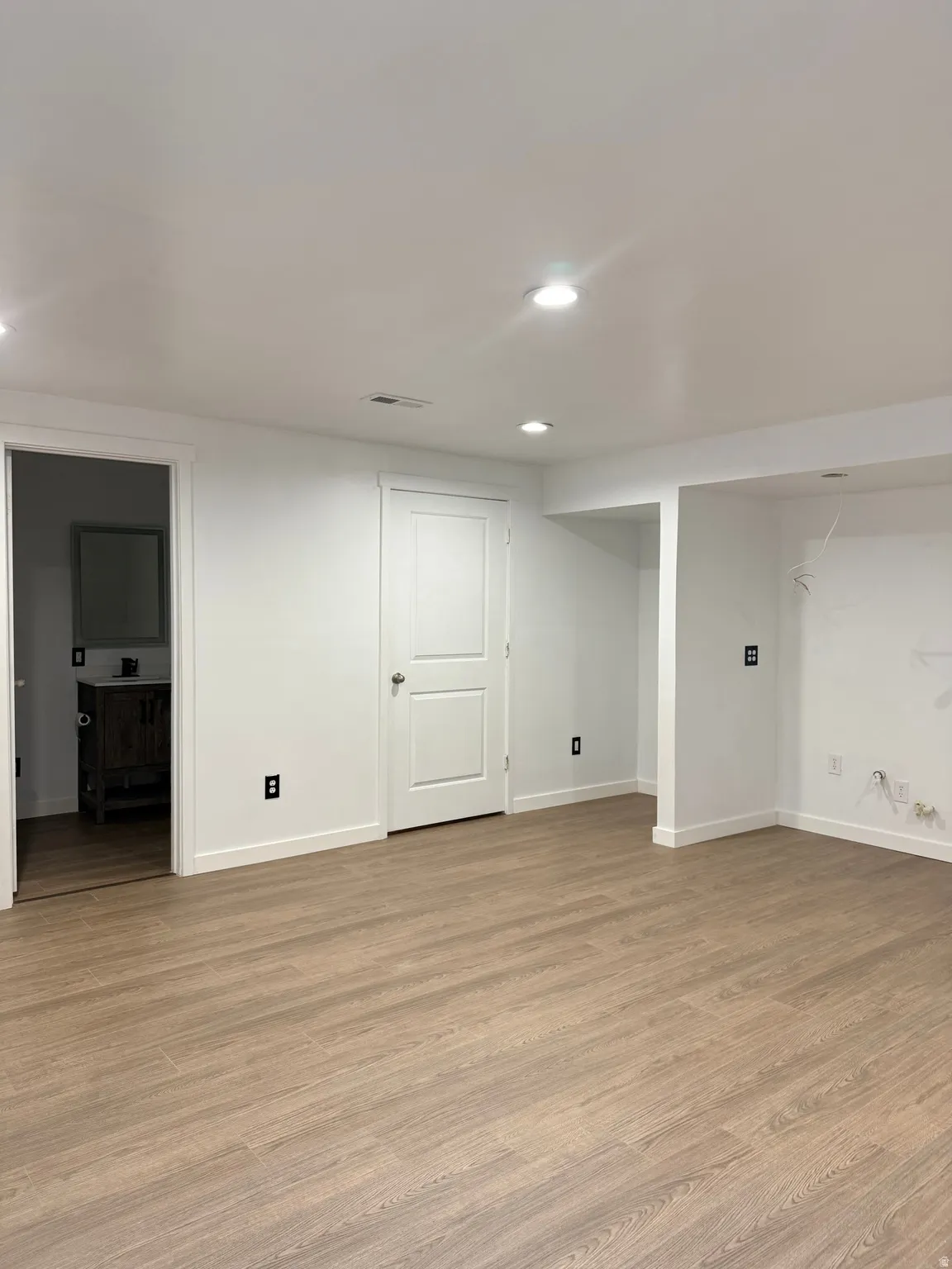 Finished basement with light wood-type flooring and recessed lighting